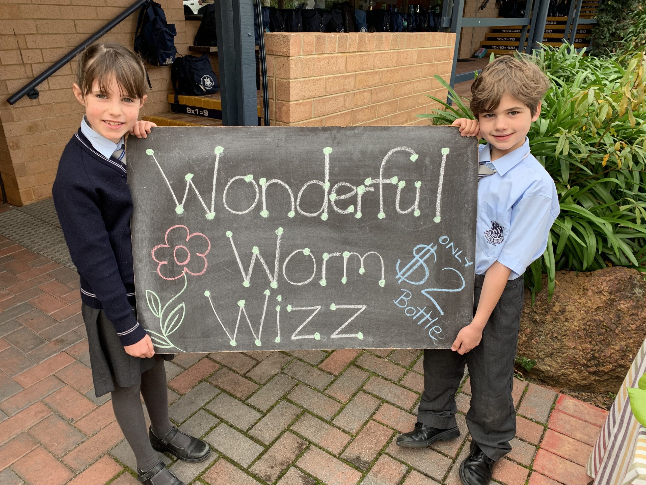 Two kids holding Wonderful Worm Wizz sign