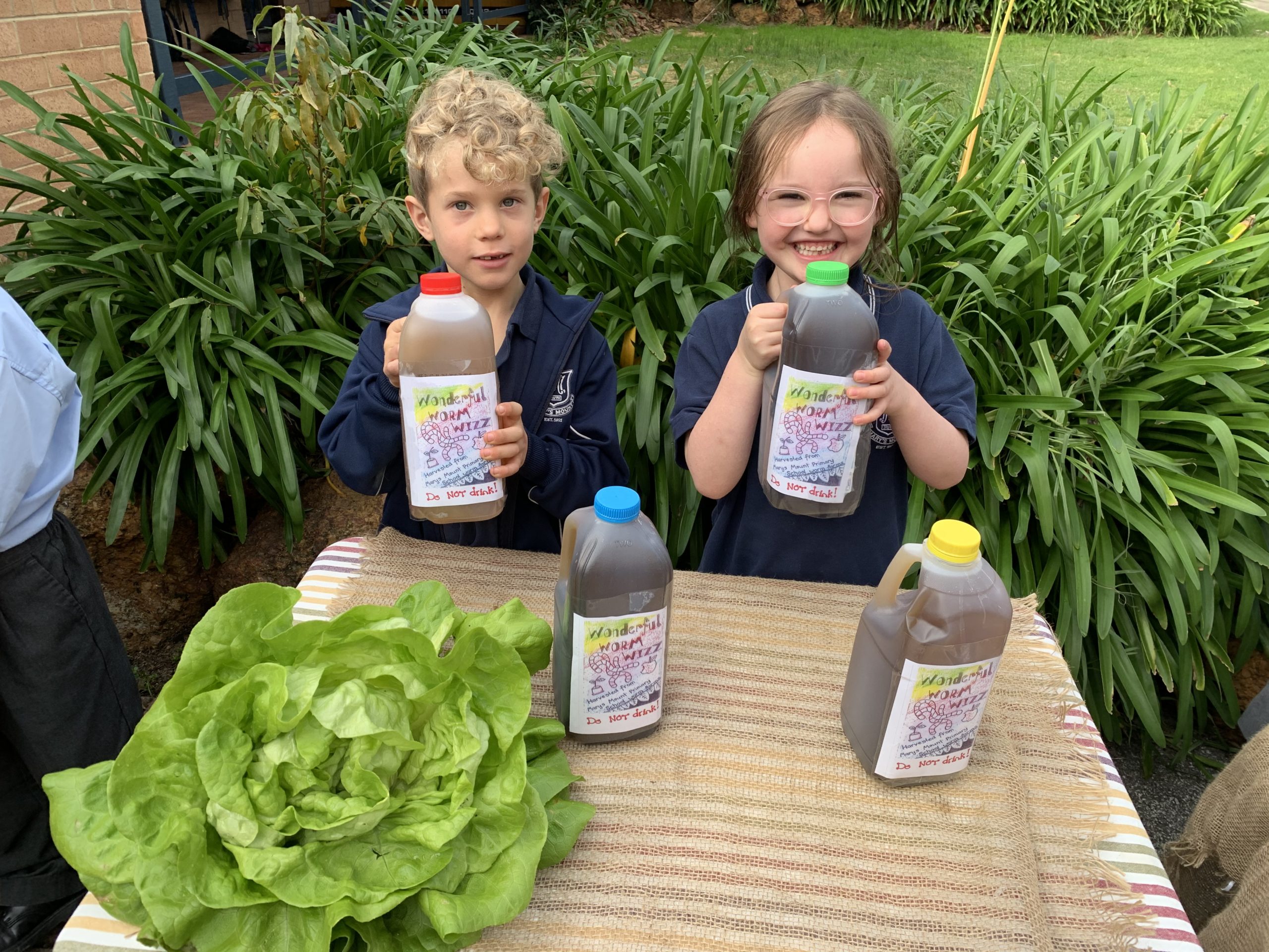 Two kids holding Worm Wizz juice bottles